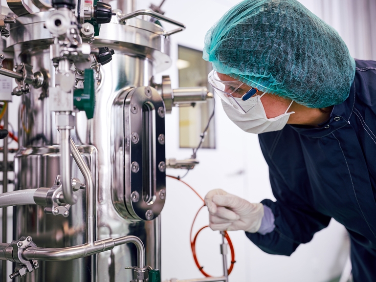 Wetenschapper met een fermentor voor biofarmaceutische productie in de life science-industrie Fermentor en wetenschapper in biofarmaceutische productie