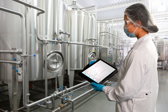 Vrouw in productievestiging in de voedingsmiddelen- en drankindustrie die de Netilion Asset Health-status controleert