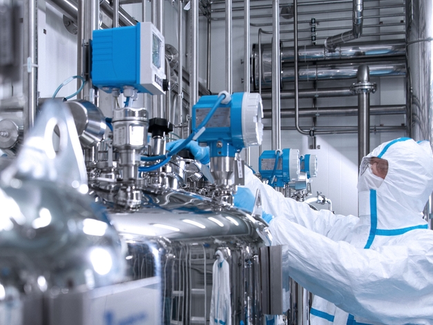 Technicus in een hygiënisch pak bezig met een instrument in een life-science-omgeving.